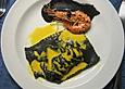 Schwarze Ravioli mit Garnelenf&uuml;llung an gelber und schwarzer Sauce